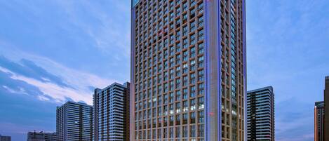 A high-rise hotel with a modern design, featuring a prominent vertical light strip and a large digital billboard at the base.