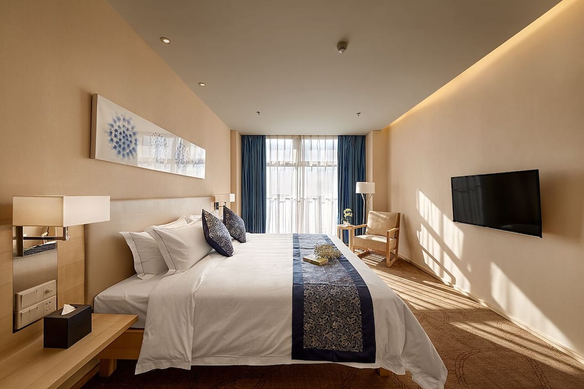 Une chambre d’hôtel avec un grand lit, des tables de chevet, un téléviseur à écran plat et une vue sur l’extérieur.