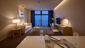 A hotel room with a balcony, a sofa, a desk, a dining table set, and a TV. - Shijiazhuang Nuohuating Hotel (Shijiazhuang)