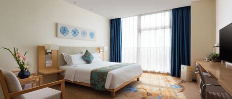 Una habitación de hotel con cama, escritorio, silla, televisión y ventana con cortinas.
