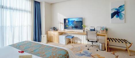 A hotel room with a bed, desk, chair, and a television displaying a welcome message.