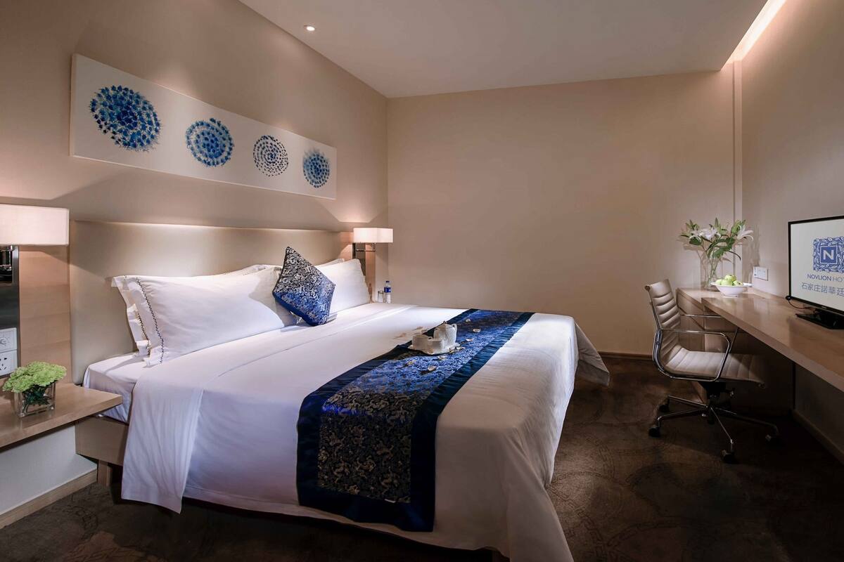Une chambre d’hôtel avec un grand lit, un bureau avec un ordinateur et une télévision.