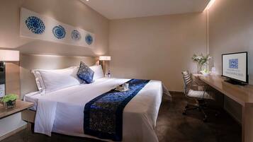 Ein Hotelzimmer mit einem großen Bett, einem Schreibtisch mit Computer und einem Fernseher.
