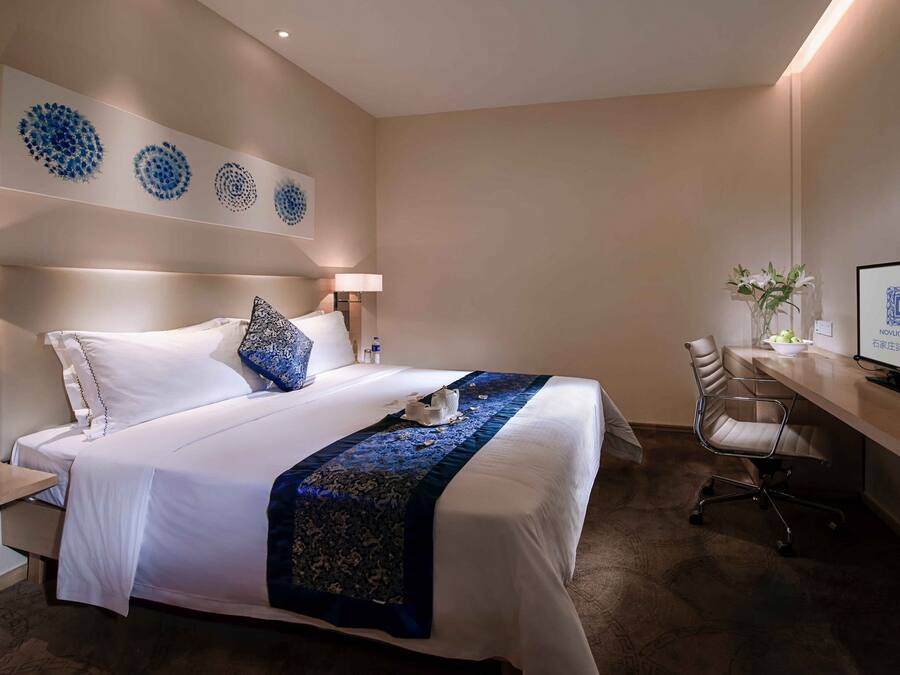 Ein Hotelzimmer mit einem großen Bett, einem Schreibtisch mit Computer und einem Fernseher.
