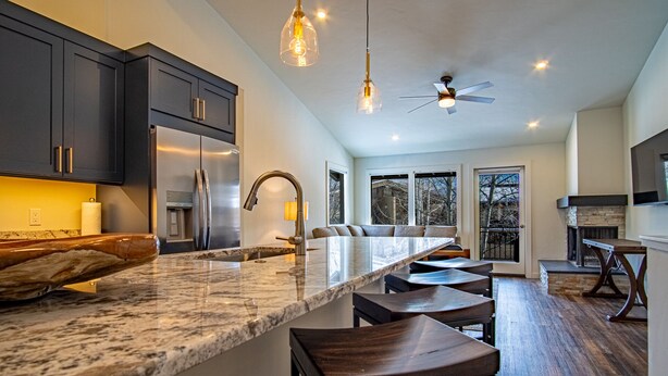 A spacious kitchen with dark cabinets, a large island, and a ceiling fan. - Steps to Free Shuttle • 3-Min Ride to Ski Lifts & Ketchum (Ketchum)