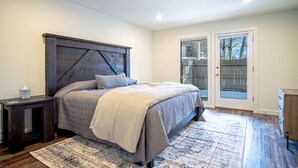 A bedroom with a large bed, a dark headboard, a bedside table, a rug, and a door with glass panels. - Steps to Free Shuttle • 3-Min Ride to Ski Lifts & Ketchum (Ketchum)
