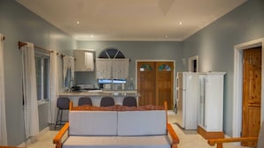 A compact living space with a sofa, dining table, kitchen area, and a refrigerator. - Majestic Villa, breathtaking view of famous Pitons, Ocean and Soufriere Town (Soufriere)