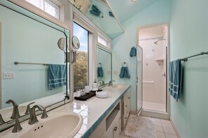 A bathroom with two sinks, a shower, and a glass-enclosed shower area.