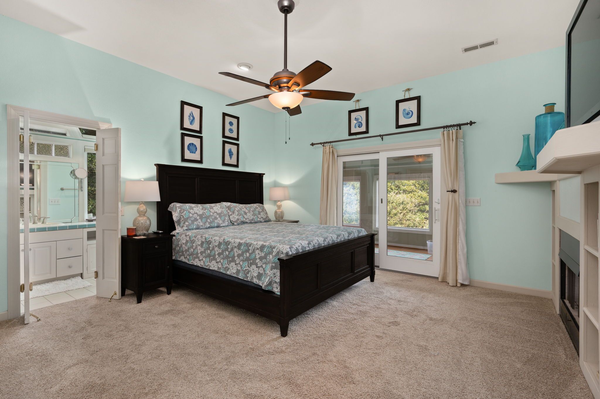 A bedroom with a bed, a ceiling fan, a window, and a door.