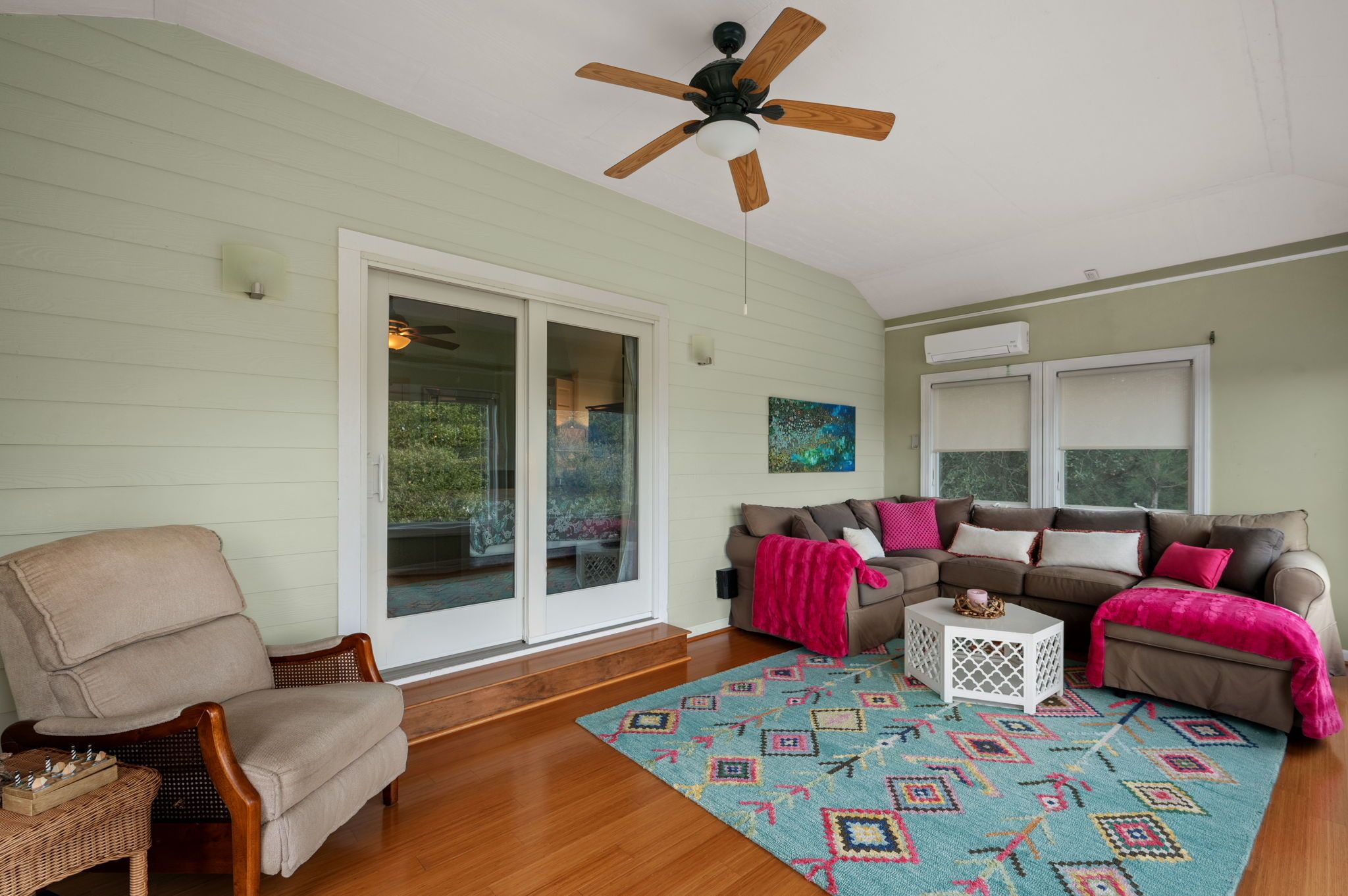 A living room with a ceiling fan, a sofa set, a coffee table, and a patterned rug.