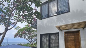 A modern two-story house with a large window and a wooden door. - Sanalae Apartments (Honiara)