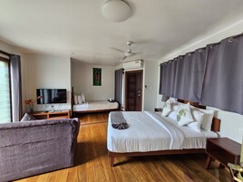 Quarto de hotel com cama, sofá, televisão e ventoinha no teto.