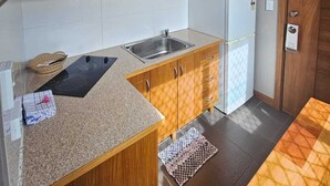 A compact kitchen with a sink, microwave, and wooden cabinets. - Sanalae Apartments (Honiara)