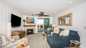 A living room with a fireplace, a TV, a sofa, and a balcony with a view. - Luxury unit - Amazing Ocean & Harbor Views - Huge Kitchen - NCV G216 (Oceanside)