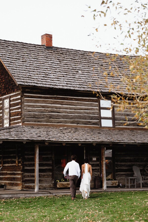 A rustic log cabin with a porch and a chimney.