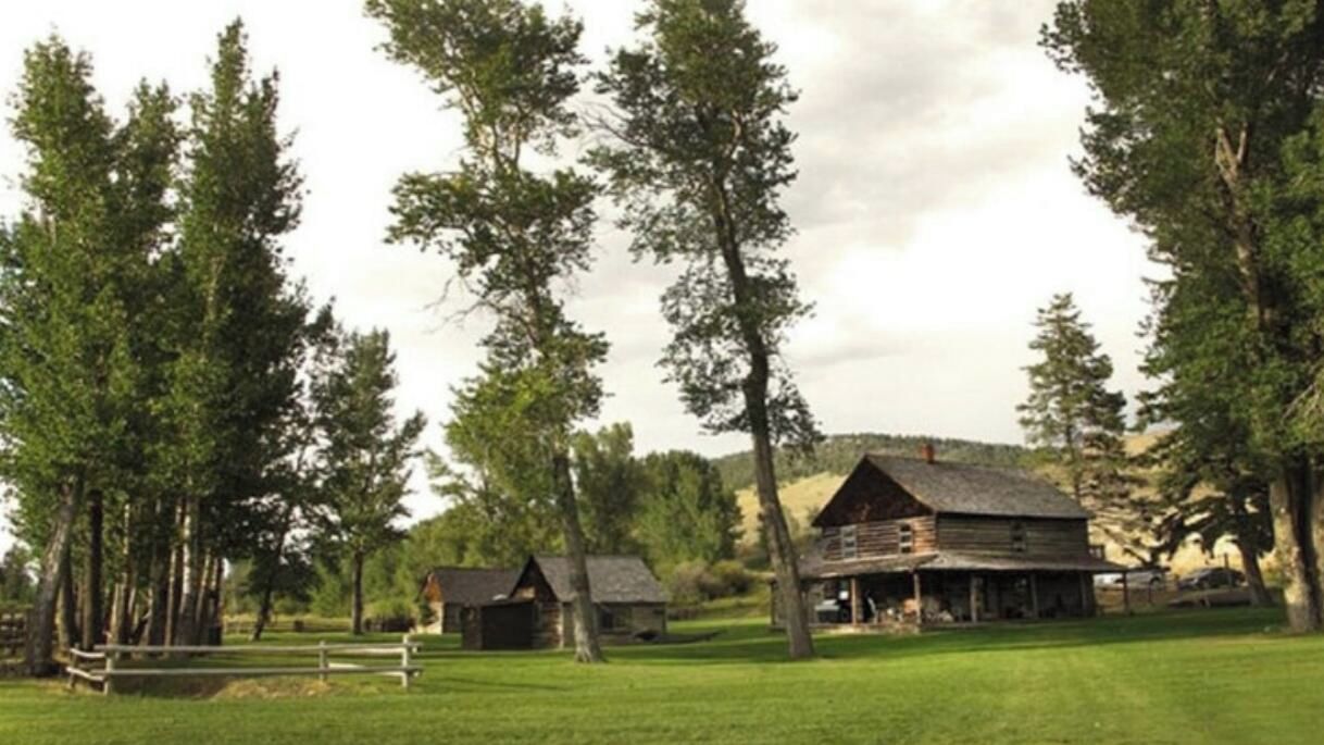 A rustic lodge with a main building and two cabins on a 12-acre property surrounded by tall trees.