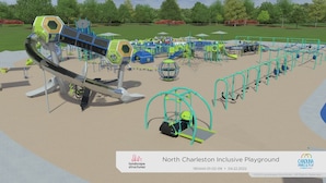 A playground with various play structures, including slides and swings, surrounded by a landscaped area.