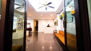 A hotel reception area with a ceiling fan, a reception desk, and a seating area. - KRABI MORE HOTEL (Krabi)