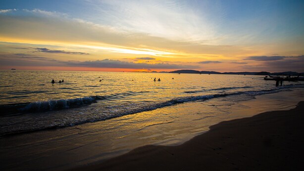 A beach at sunset with calm waters, a pier, and distant mountains. - KRABI MORE HOTEL (Krabi)