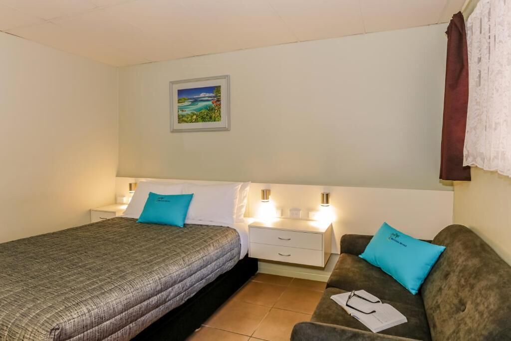 A bedroom with a bed, a nightstand, a dresser, and a couch.