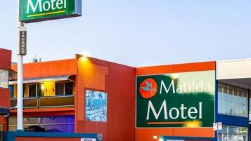 Een motel met een opvallend groen bord, een zwembadgedeelte en een duidelijke ingang.