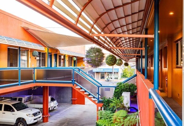 Una estructura de estacionamiento de varios niveles con un pasillo cubierto, una escalera y vista a la calle.
