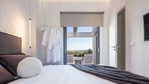 Een moderne slaapkamer met een groot bed, uitzicht en een balkon met een tafel en stoelen.