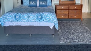 A bedroom with a bed, a dresser, a mirror, and a wall decoration.