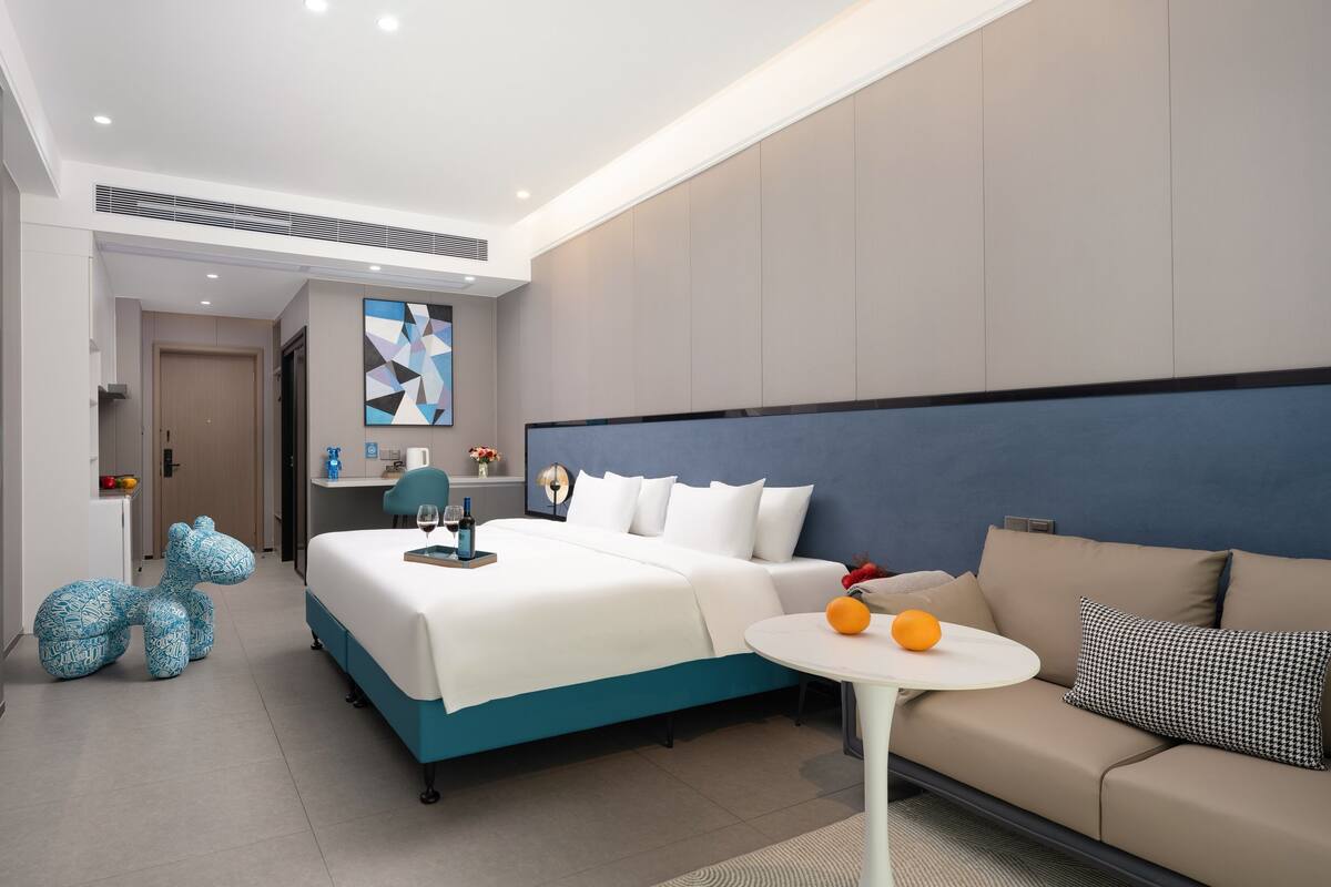 Una habitación de hotel moderna con una cama grande, un sofá, una mesita redonda y un escritorio con una silla.