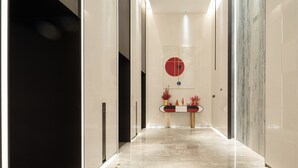 A modern hallway with a marble floor, a central art piece, and a console table with decorative items. - Yutai hotel-Style Apartment (Shenzhen)