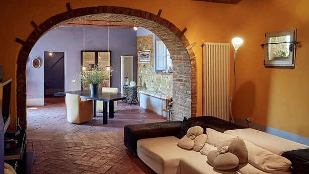 A cozy living area with a stone archway, a dining table with chairs, and a sofa with cushions. - Beautiful private villa for 11 people with WIFI, A/C, private pool, TV, patio and panoramic view (Bobolino)