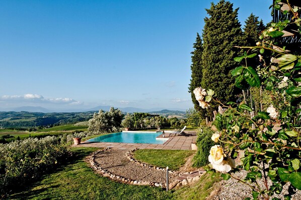 A pool area with a view of distant hills and a garden with roses. - Wonderful private villa for 6 guests with WIFI, A/C, private pool, TV, patio and panoramic view (Botinaccio)