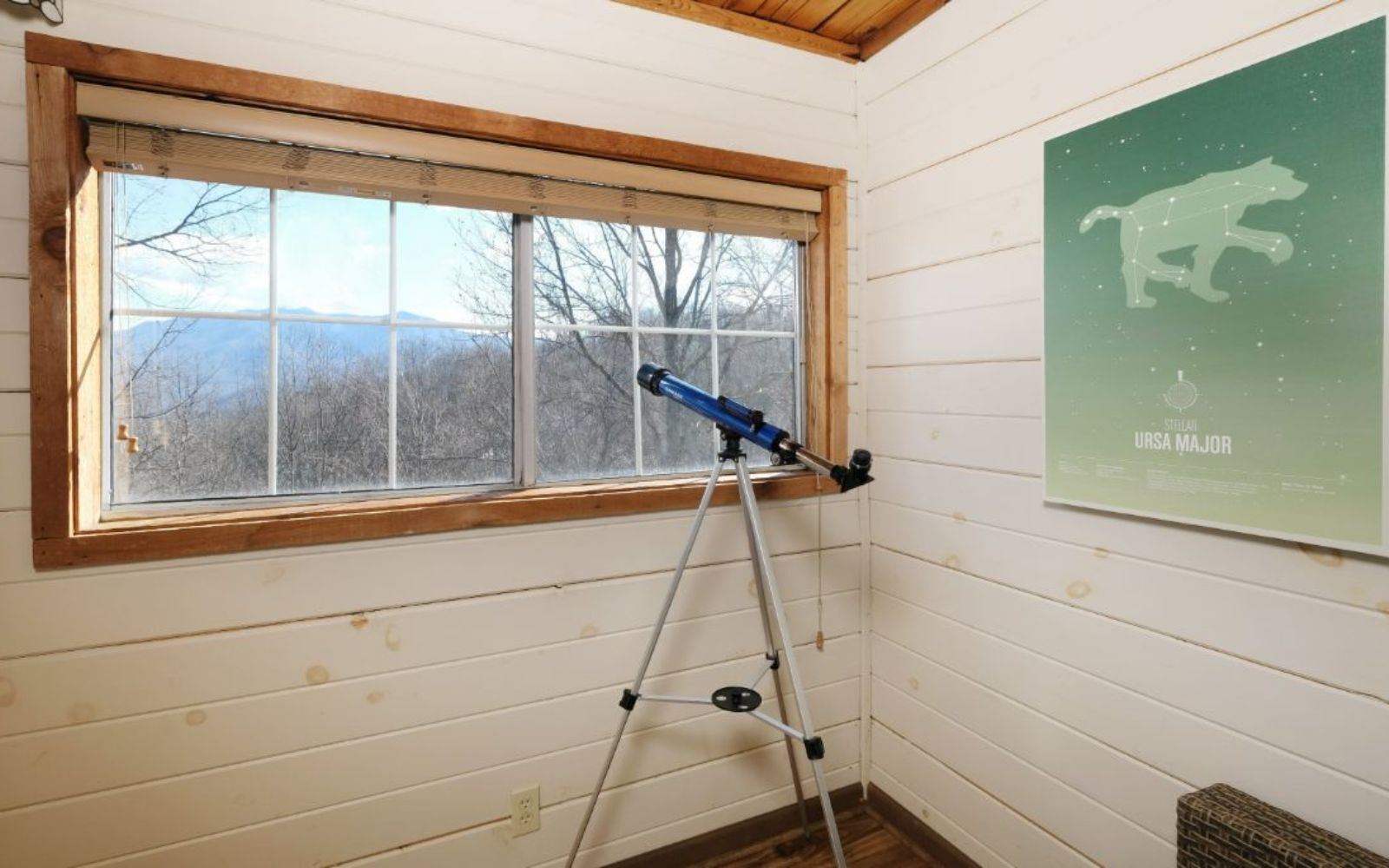 Ein Zimmer mit einem Teleskop am Fenster mit Blick auf eine verschneite Landschaft.