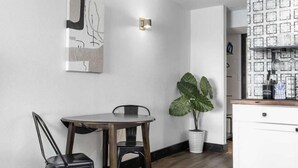 A dining area with a wooden table and chairs, a potted plant, a wall-mounted light fixture, and a white cabinet with patterned glass doors. - Sea Mist 21006 (Myrtle Beach)