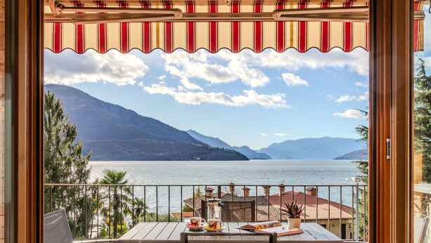 A balcony with a table and chairs, overlooking a lake with mountains in the background. - Cristina by Interhome (Gravedona)
