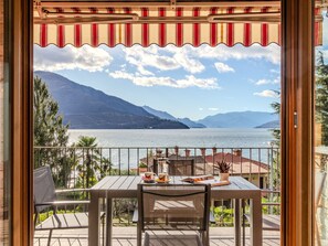 A balcony with a table and chairs, overlooking a lake with mountains in the background. - Cristina by Interhome (Gravedona)
