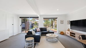 Una sala de estar moderna con un sofá modular, un televisor y un ventanal grande.
