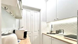 A compact kitchen with white cabinets, a microwave, a kettle, and a coffee maker on the countertop. - AAA STAY PREMIUM Old Town Mariensztat (Warsaw)