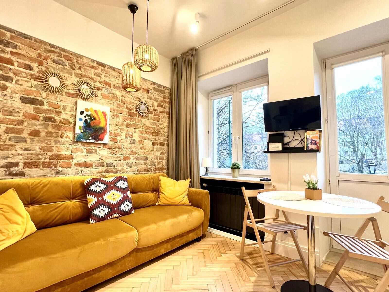 A cozy living area with a sofa, a dining table, and a TV mounted on the wall.