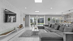 A modern living room with a grey sofa, a coffee table, and a TV mounted on the wall. - 15BD Sonoma Resort Luxury House  (SR2609) (Kissimmee)