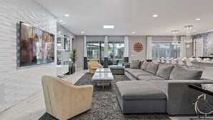 Ein modernes Wohnzimmer mit einem Ecksofa, einem Couchtisch und einem an einer weißen Ziegelwand montierten Fernseher.