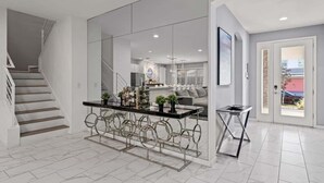 Ein modernes Interieur mit Treppe, einer Glastrennwand, einem Essbereich mit Tisch und Stühlen sowie einem Ausblick durch eine Tür.
