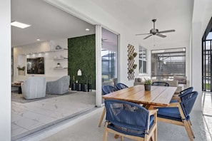 Et moderne spiseområde med et træbord og blå stole, en grøn væg og en loftsvifte.