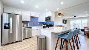 Una cocina moderna con electrodomésticos de acero inoxidable, una isla central con taburetes y un ventanal con vistas.