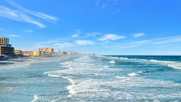 Un paisaje urbano costero con playa, edificios y olas.