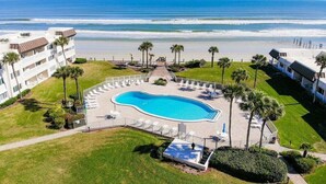 Un hotel con piscina, vistas a la playa y palmeras.