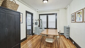 A dining area with a wooden table and chairs, a black cabinet, and a radiator. - The Inn Too @ The Highland Hill (Akron)