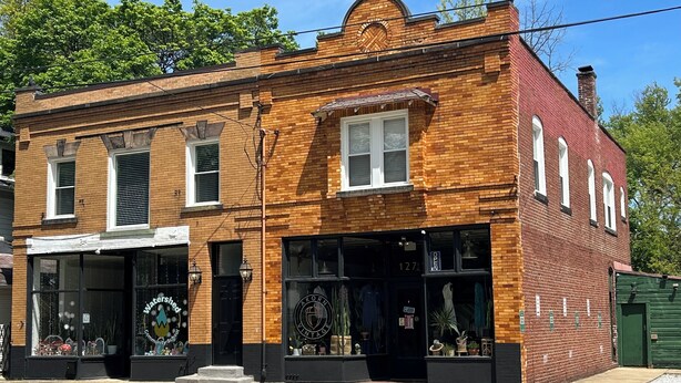 A two-story brick building with large windows and a storefront. - The Inn Too @ The Highland Hill (Akron)