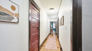 A hallway with a wooden floor, a red door, and a patterned rug. - The Inn Too @ The Highland Hill (Akron)