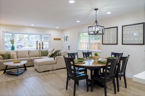 A modern living room with a sofa, a coffee table, and a dining area with a table and chairs. - Historic Roseville Retreat with Hot Tub (Roseville)